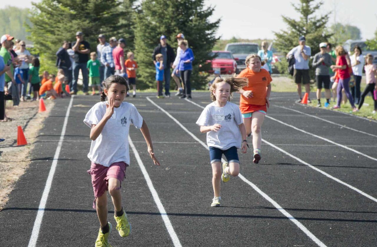 Youth track and field meet with kids at starting blocks and a volunteer coordinator